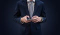 Businessman in dark blue suit using mobile smart phone, on blue background