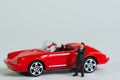 a businessman with dark suit in front of his red sports car, miniature figures scene, toy car Royalty Free Stock Photo