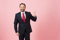 Businessman in dark suit thumb up on pink pastel background isolated in studio. Royalty Free Stock Photo