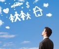 Businessman daydreaming with family and household clouds