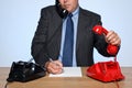 Businessman at desk answering two telephones. Royalty Free Stock Photo