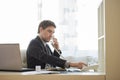 Businessman dialing telephone number sitting at his office desk