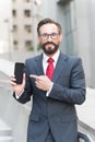 Businessman and digital gadget. Portrait of smiling businessman pointing finger at blank screen mobile phone Royalty Free Stock Photo