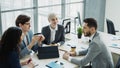 Businessman discussing future business project with male and female colleagues sitting at the table in modern office Royalty Free Stock Photo