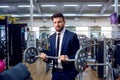 Businessman doing exercises with barbell in the gym