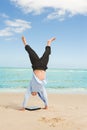 Businessman doing handstand on the beach