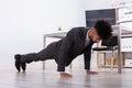 Businessman Doing Push Up In Office