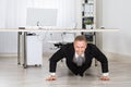 Businessman Doing Pushup At Work