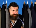 Businessman with doubtful face against row of suits in shop Royalty Free Stock Photo