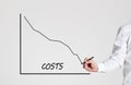 Businessman draws a declining line graph with the word costs. Decreasing business costs Royalty Free Stock Photo