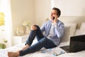 Businessman talking on the phone sitting on a bed