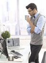 Businessman drinking coffee standing in office Royalty Free Stock Photo
