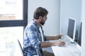 Businessman drinking coffee while working on desktop computer. Mature man using computer while sitting on chair. Businessman using Royalty Free Stock Photo