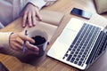 Businessman drinking coffee and working on laptop computer, mobile phone, writing business plan, wearing white shirt Royalty Free Stock Photo