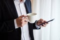 Businessman drinks coffee and looks at the phone