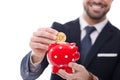 Businessman drop one bitcoin into red dotted piggy bank closeup