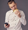 Man eat hamburger in cafe while watch video on his phone Royalty Free Stock Photo