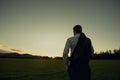 Businessman in elegant suit with his jacket hanging over his shoulder standing in mown field Royalty Free Stock Photo