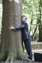 Businessman Embracing Tree Trunk In Forest Royalty Free Stock Photo