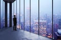 Businessman in empty office looking out of panoramic window with bright city downtown view. Future, tomorrow, perspective and Royalty Free Stock Photo