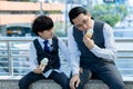 Businessman enjoy eating ice cream with his business son. Handsome son look his father eating ice cream in a city during taking a