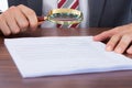 Businessman examining document with magnifying glass