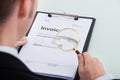 Businessman examining invoice through magnifying glass Royalty Free Stock Photo