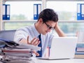 Businessman with excessive work paperwork working in office