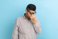 Businessman in eyeglasses rubbing his eyes, being tired of long hours working on laptop.