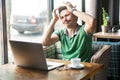 Businessman feeling sorry and blaming himself for the mistake while working on laptop in cafe.