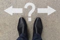 Businessman feet in shoes standing on asphalt road markings with arrows pointing left and right with question mark. Pair of feet Royalty Free Stock Photo