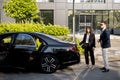 Businessman and female chauffeur near car outdoors