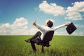 businessman in a field with a blue sky sitting on an office chair and waving his arms Royalty Free Stock Photo