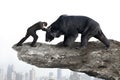 Businessman fighting against black bear on cliff with sky citysc