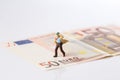 Businessman figurine running on a euro banknote