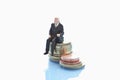 Businessman figurine sitting on stack of euro coins