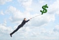 Businessman floating up in sky holding big green dollar sign on atring.