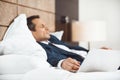 Businessman in formal suit falling asleep on bed in hotel room Royalty Free Stock Photo