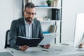 Businessman in formal wear and glasses holding paper and notebook Royalty Free Stock Photo