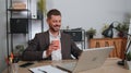 Businessman enters office start working on laptop computer at desk and drinking morning coffee