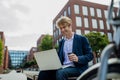 Businessman, freelancer or manager working outdoors in city park. Man with laptop on knees drinking coffee, having video Royalty Free Stock Photo