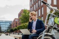 Businessman, freelancer or manager working outdoors in city park. Man with laptop on knees having video call. Concept of Royalty Free Stock Photo