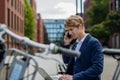Businessman, freelancer or manager working outdoors in city park. Man with laptop on knees making call on smartphone Royalty Free Stock Photo