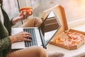 Businessman freelancer surfing internet on laptop and eating pizza