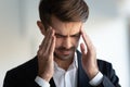 Businessman frown face closed eyes touches temples reduces migraine pain