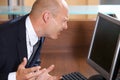 Businessman frowning in front of computer monitor