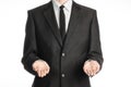 Businessman and gesture topic: a man in a black suit and tie holding two hands in front isolated on white background in studio