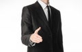 Businessman and gesture topic: a man in a black suit and tie holds out his hand to greet isolated on white background in studio