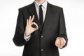 Businessman and gesture topic: a man in a black suit with a tie showing okay sign with his left hand and holds his right hand on Royalty Free Stock Photo