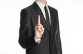 Businessman and gesture topic: a man in a black suit with a tie shows an index finger upward on white isolated background in